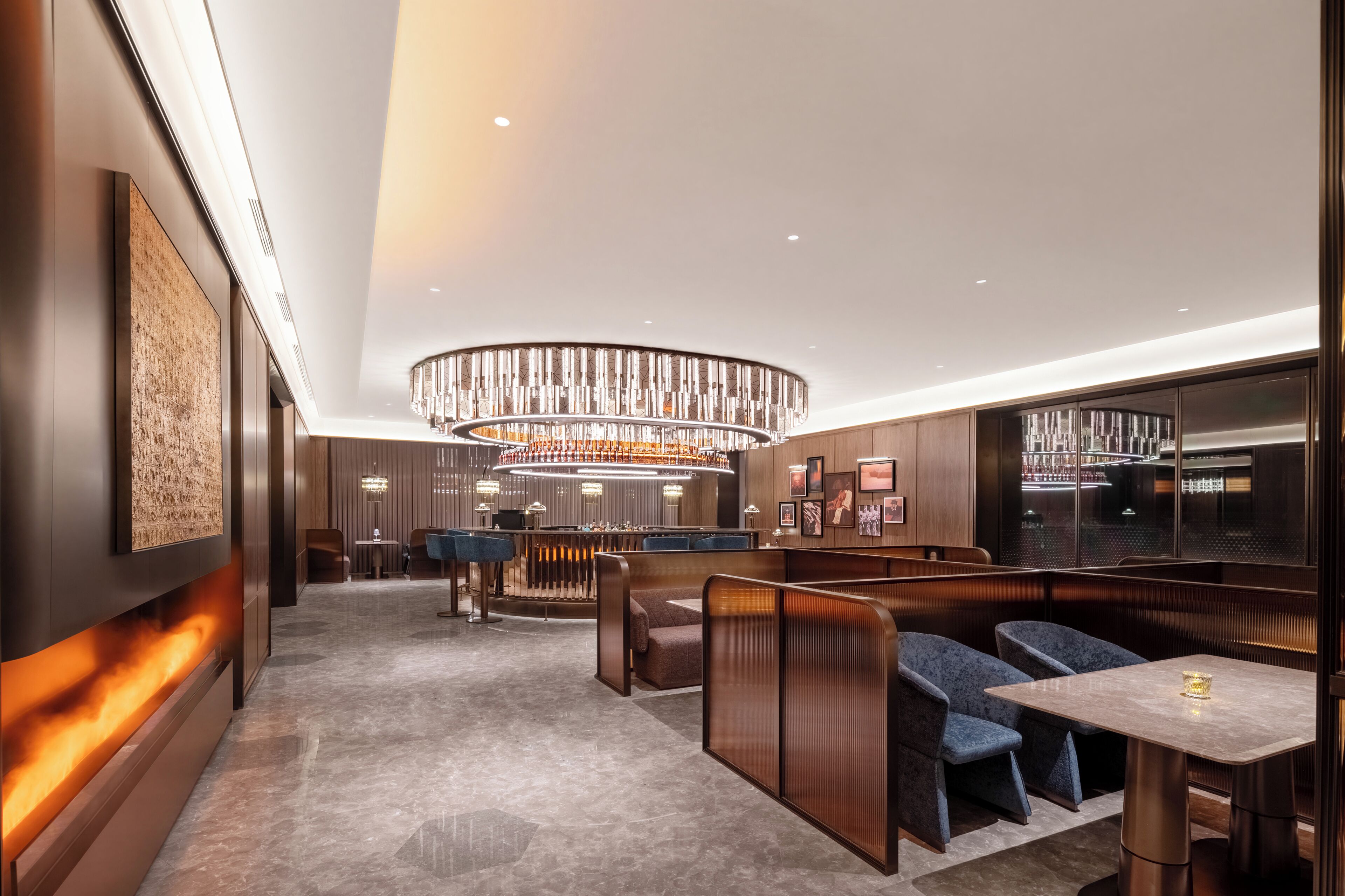 A modern hotel lobby with a bar area, seating, and a decorative ceiling light.