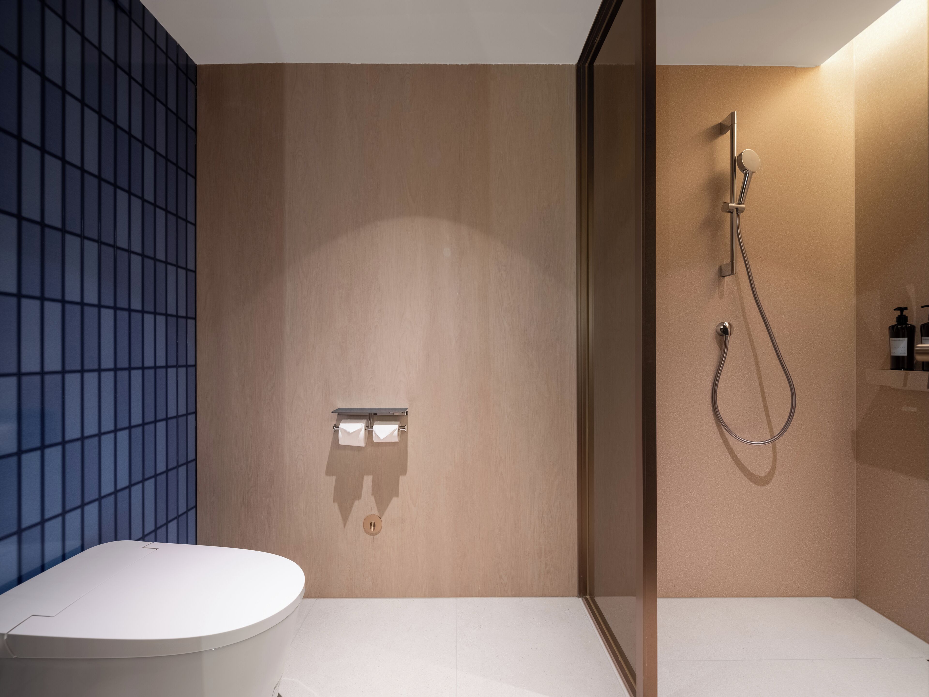 Un baño moderno con inodoro, ducha y perchero.