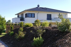 Ein modernes, zweistöckiges Haus mit einer Steinwand, einem Balkon und einem gepflegten Garten.
