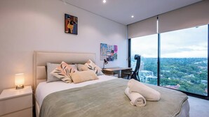 Et moderne hotelværelse med en stor seng, et skrivebord og udsigt over bybilledet.