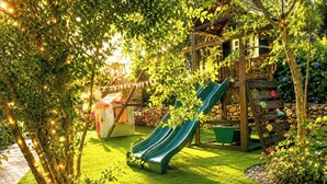 Een speeltuin met een glijbaan, een huisje en een houten constructie.