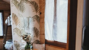 Un interior de madera con un banco, una mesita y una ventana con cortinas.