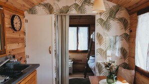 Un interior de madera con cocina, una mesa de comedor con un florero y una cama con vista al exterior.