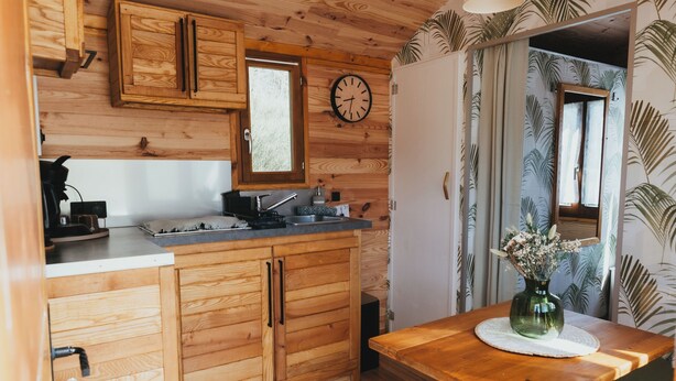 Una cocina de madera con un lavamanos, armarios y un reloj.