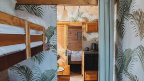 Una habitación compacta con literas, una kitchenette pequeña y techo de madera.