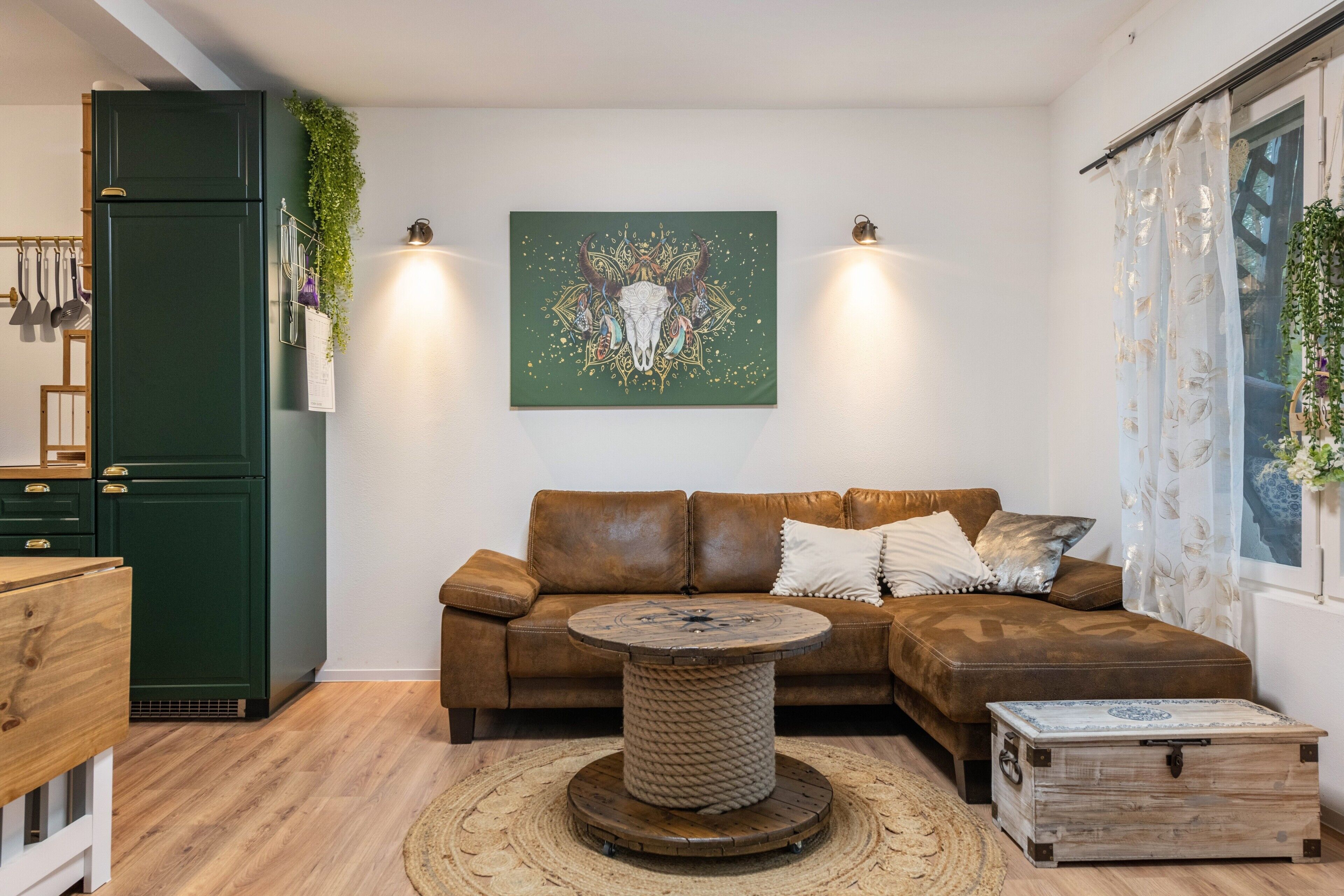Ein modernes Wohnzimmer mit einem grünen Schrank, einem braunen Ledersofa, einem runden Couchtisch und einer Wanddekoration.