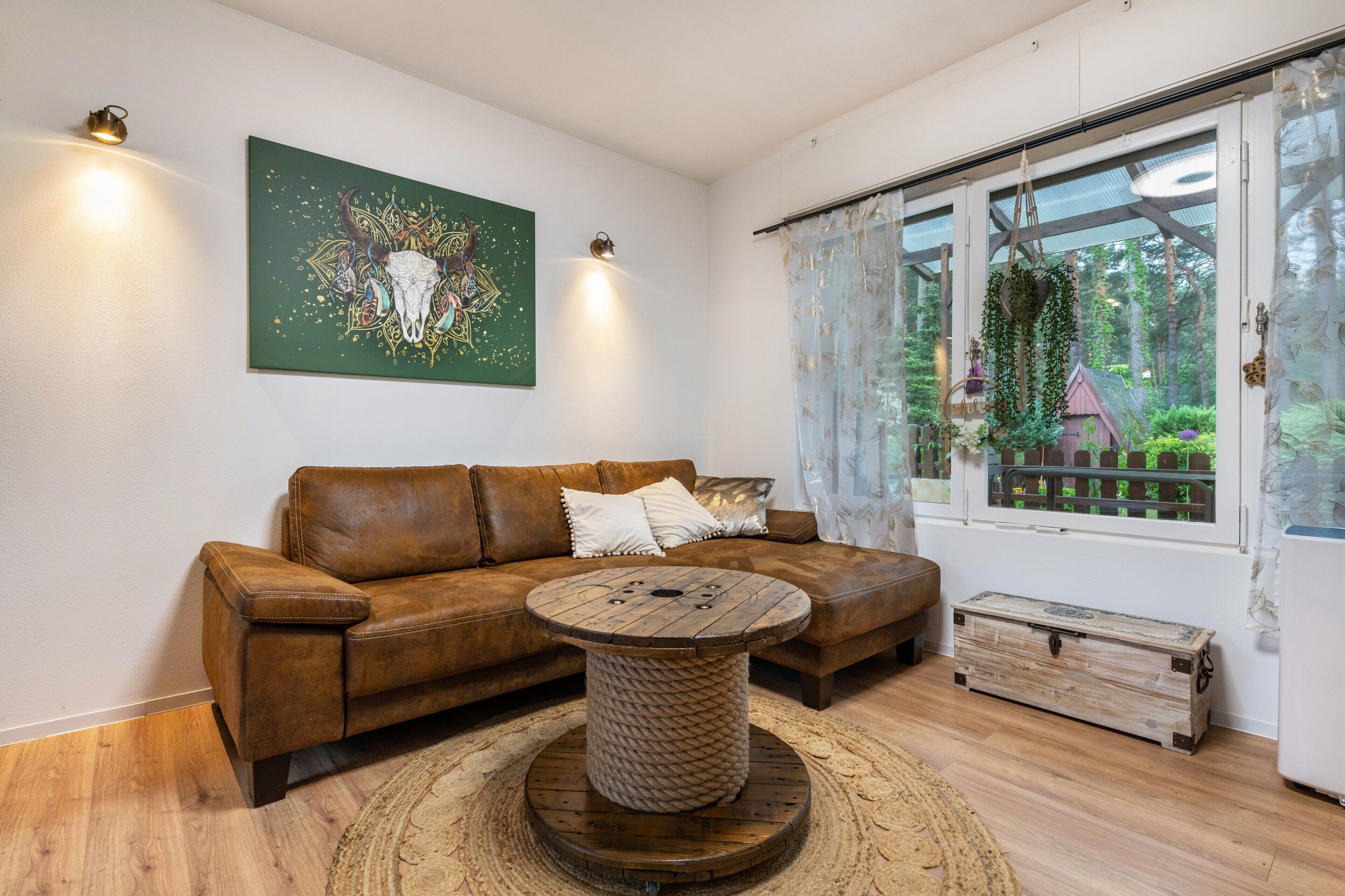 A living room with a brown leather sofa, a round wooden coffee table, and a green abstract painting on the wall.