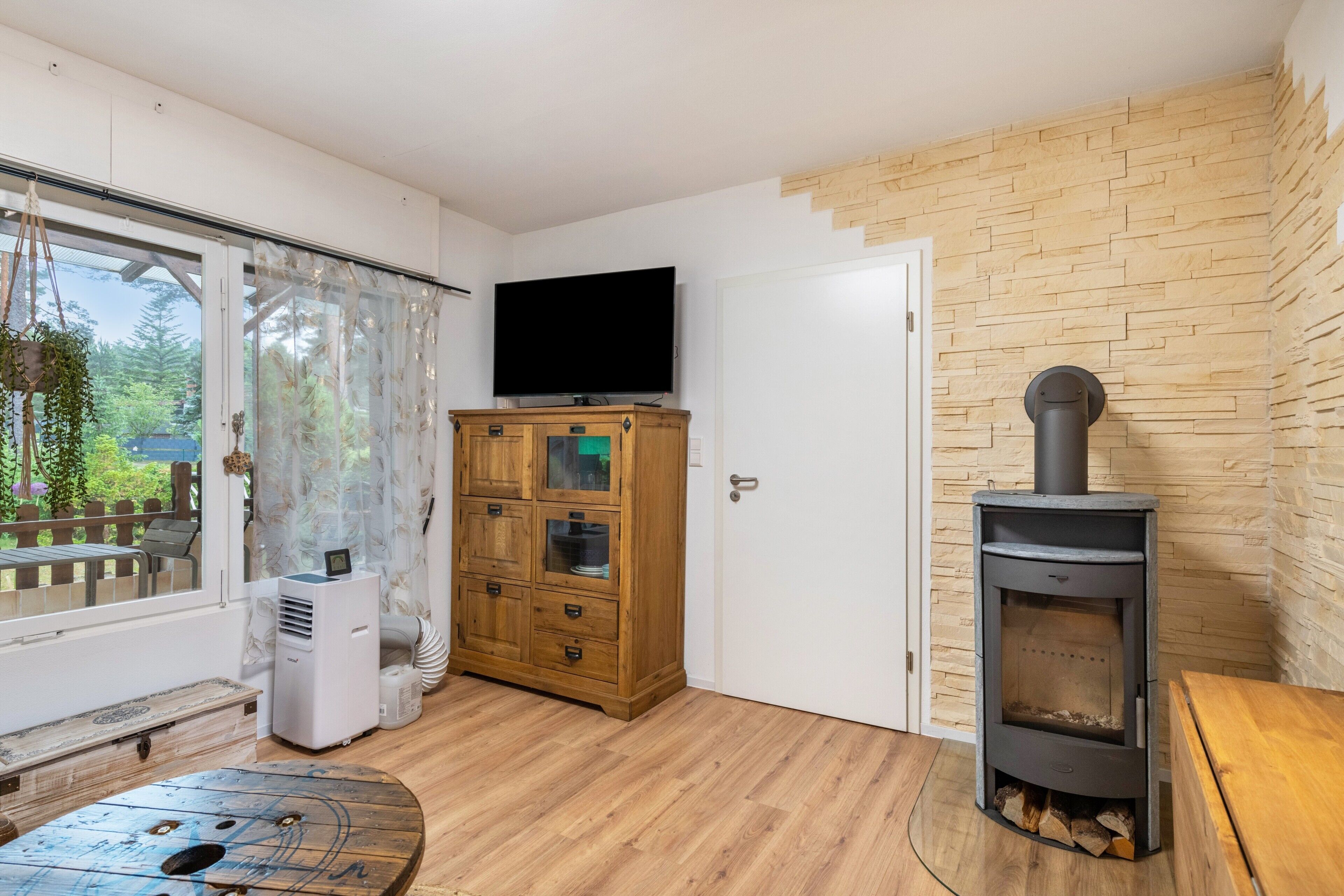 Ein Zimmer mit einem Holzkasten, einem Fernseher, einem Kamin und einer Bank.