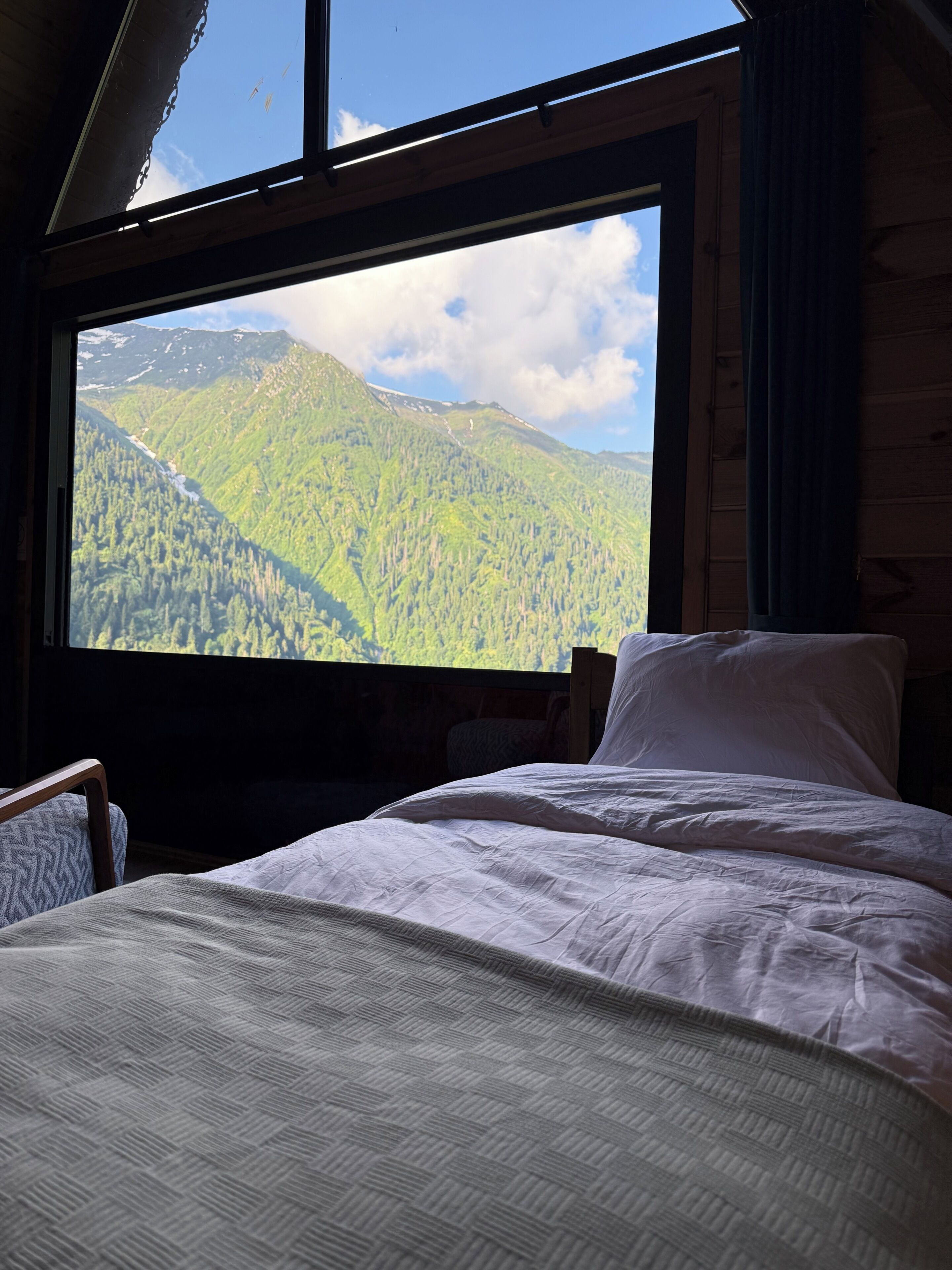 Une chambre avec un lit, une chaise et une grande fenêtre donnant sur les montagnes.
