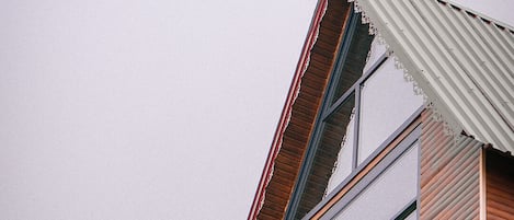 A modern building with a sloped roof, large windows, and a wooden structure.