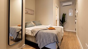 Quarto com cama, espelho, mesa de cabeceira, planta e ar condicionado.