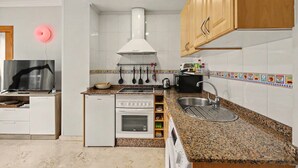 Een moderne keuken met een inbouwoven, een magnetron, een spoelbak en houten kastjes.