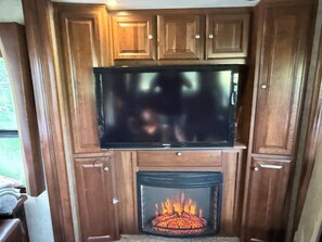 Eine Holzkommode mit einem flachbildfernseher über einem Kamin.