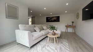 Ein modernes Wohnzimmer mit einer Couch, einem Couchtisch, einer Pflanze, einem Fernseher und einer Weltkarte an der Wand.