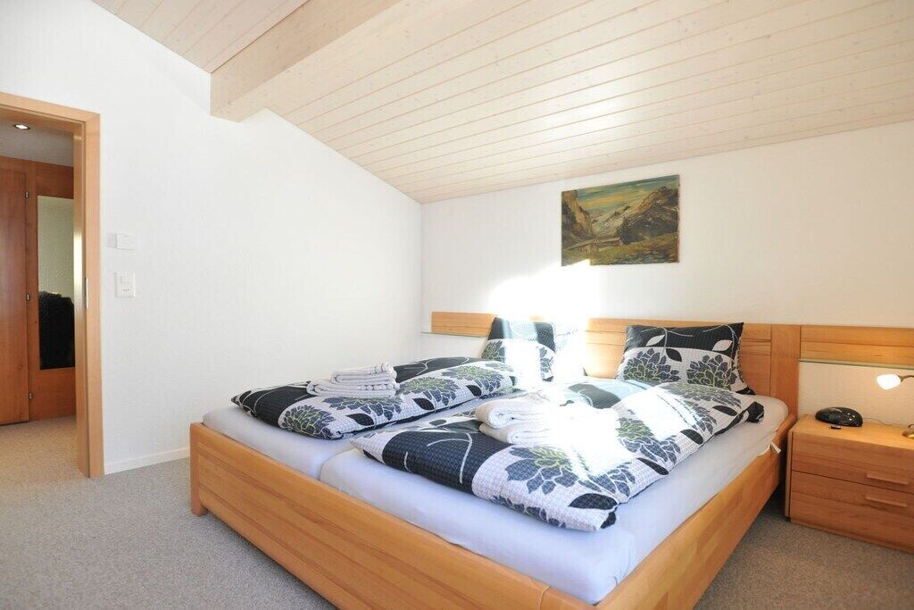 Une chambre à coucher avec un lit en bois, une table de chevet, une lampe fixée au mur et un tableau.