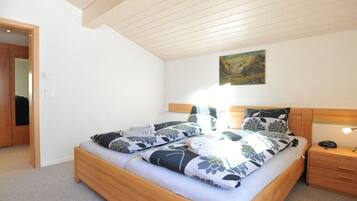 Une chambre à coucher avec un lit en bois, une table de chevet, une lampe fixée au mur et un tableau.