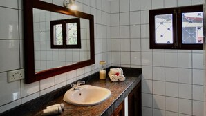 Een badkamer met een wastafel, spiegel en raam met uitzicht.