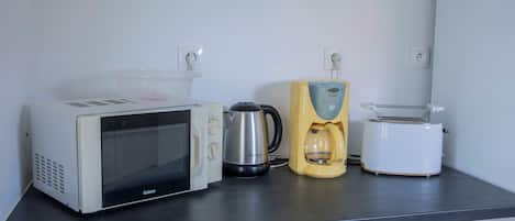 A kitchenette with a microwave, coffee maker, and toaster on a countertop.