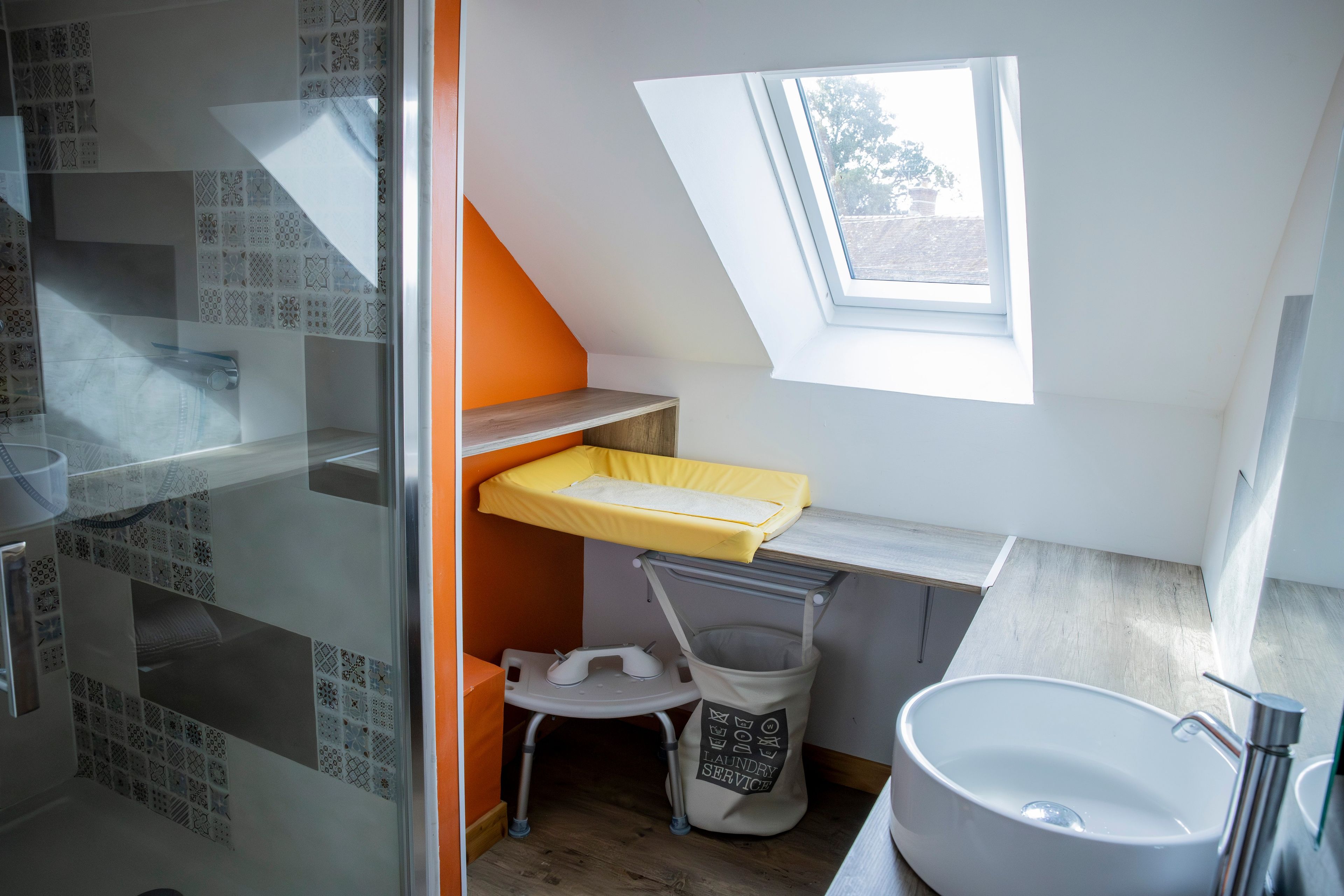 Une petite salle de bain avec un puits de lumière, un lavabo et une petite fenêtre.