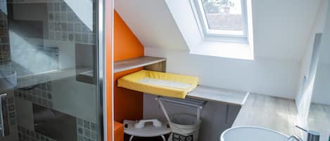 A compact bathroom with a skylight, a sink, and a small window.