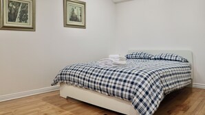 Un dormitorio con una cama, paredes blancas y dos cuadros en la pared.