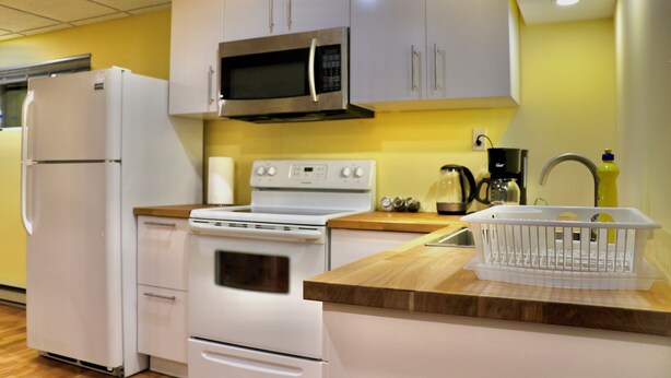 Una cocina con electrodomésticos blancos, encimera de madera y un lavabo con escurreplatos.