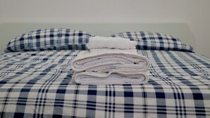 Una cama con una colcha a cuadros y dos almohadas a juego.