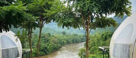 A view from a covered outdoor area with a river and trees in the background.