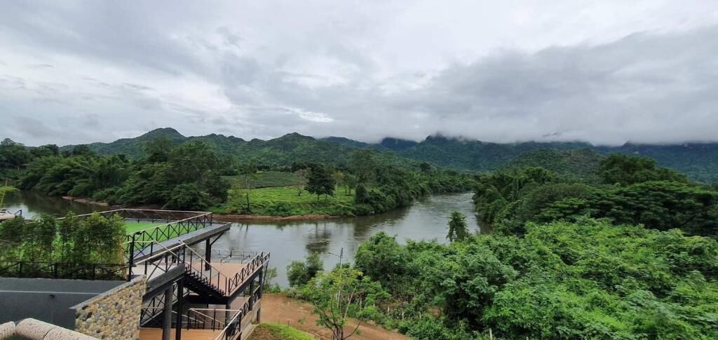 A river with a bridge and lush greenery in the background.