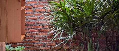 A brick wall with a wooden bench and potted plants.