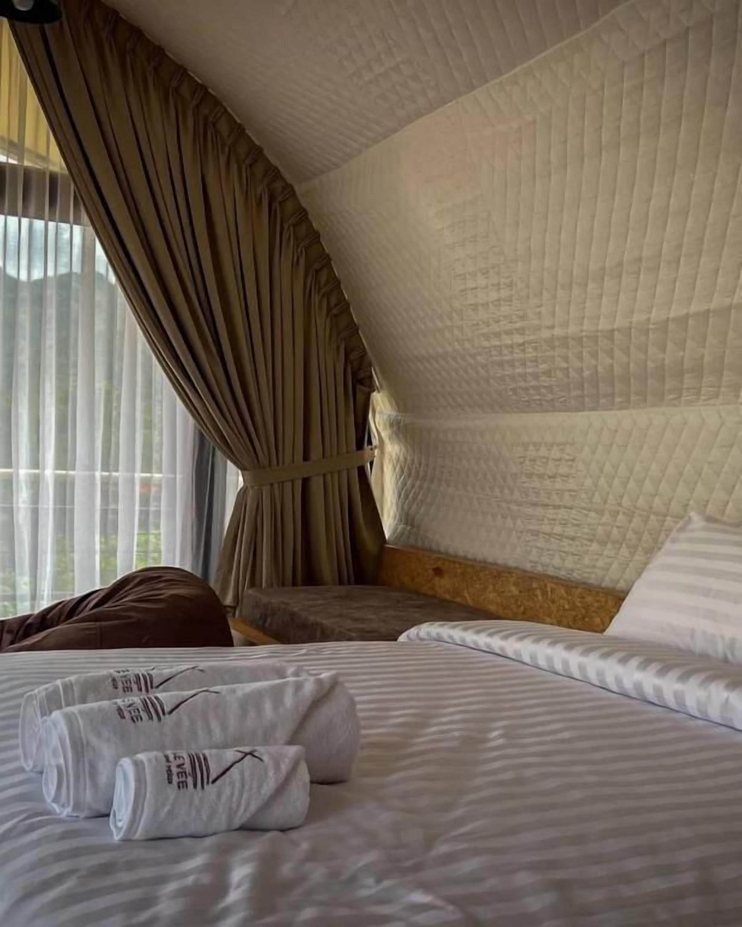 A hotel room with a curved ceiling, a bed with white linens, and a window with curtains.