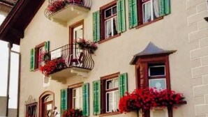 A multi-story building with balconies, green shutters, and flower boxes. - Ferienwohnungen Chasa Valär, (Scuol) by Interhome (Scuol)