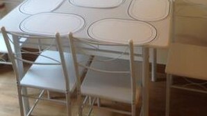 A dining table with four oval-shaped surfaces, surrounded by four chairs. - Ferienwohnungen Chasa Valär, (Scuol) by Interhome (Scuol)