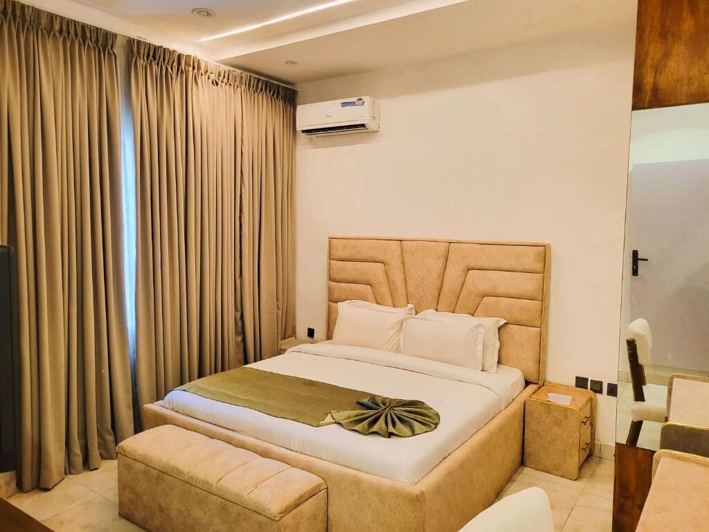 A bedroom with a large bed, a bedside table, a chair, and a mirror.
