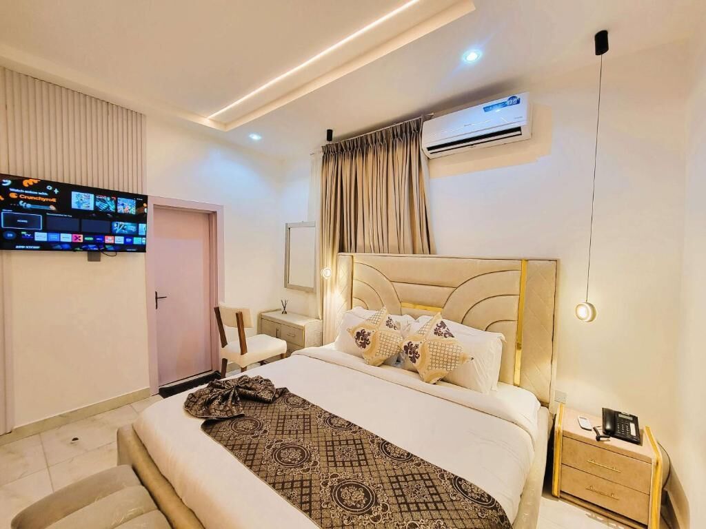 Une chambre d’hôtel moderne dotée d’un grand lit, d’un téléviseur à écran plat fixé au mur, d’un système de climatisation et d’une table de chevet avec un téléphone.