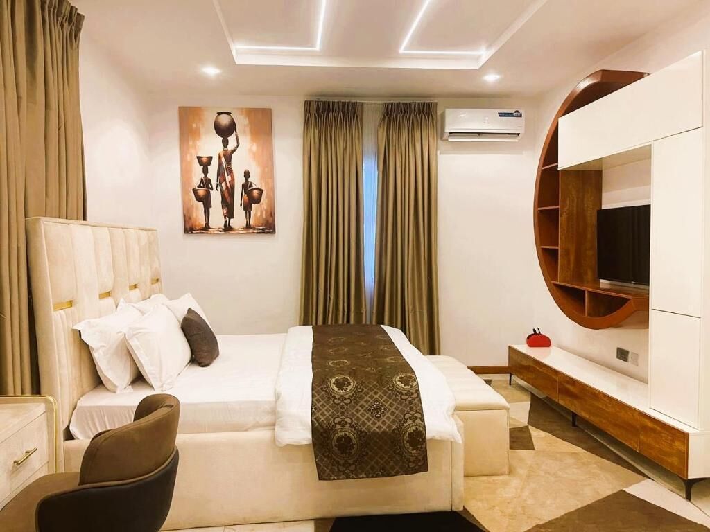Une chambre d’hôtel avec un lit, un bureau, une chaise, une télévision et un tableau au mur.