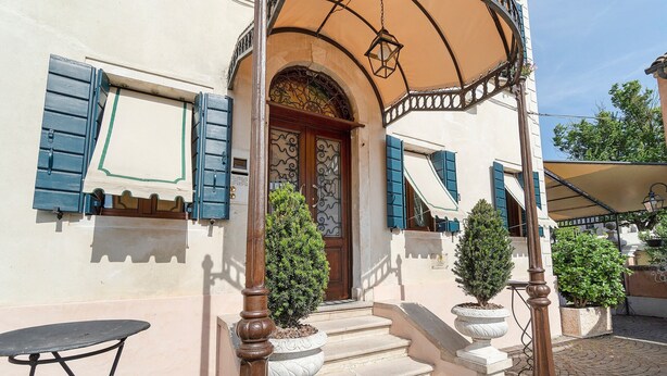 Un edificio con una entrada tradicional, una escalera que lleva a la puerta y una pequeña mesa afuera.