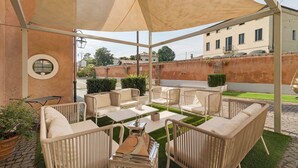Un patio exterior con mobiliario de mimbre, una mesa y un toldo.