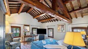 Una habitación con cama, una silla, un escritorio, un televisor y una ventana.