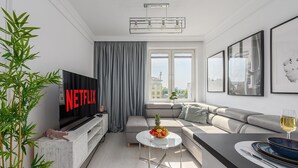 Un salon moderne doté d’un téléviseur à écran plat, d’un canapé, d’un coin repas et d’une grande fenêtre.