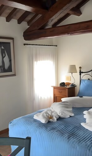A bedroom with a bed, a nightstand, a lamp, a framed picture, and a window with curtains. - Room 'Villa Goetzen - Camera Singola' with Wi-Fi and Air Conditioning (Dolo)