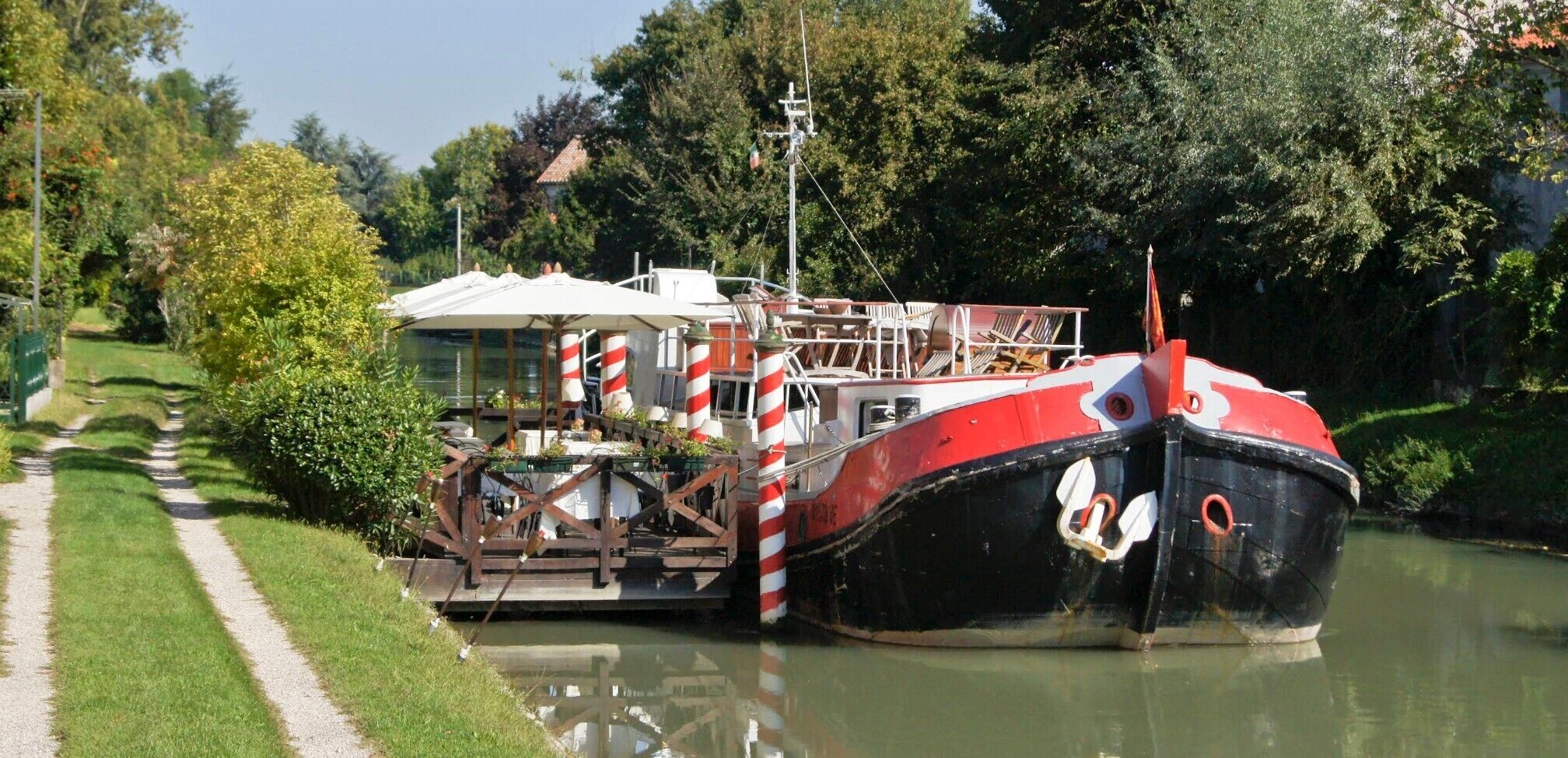 Une péniche était amarrée à un canal, et un sentier bordé d’herbe longeait le canal.
