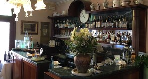 Eine Bar mit einer Uhr, Regalen voller Spirituosenflaschen, einer Vase mit Blumen und einem Aquarium.