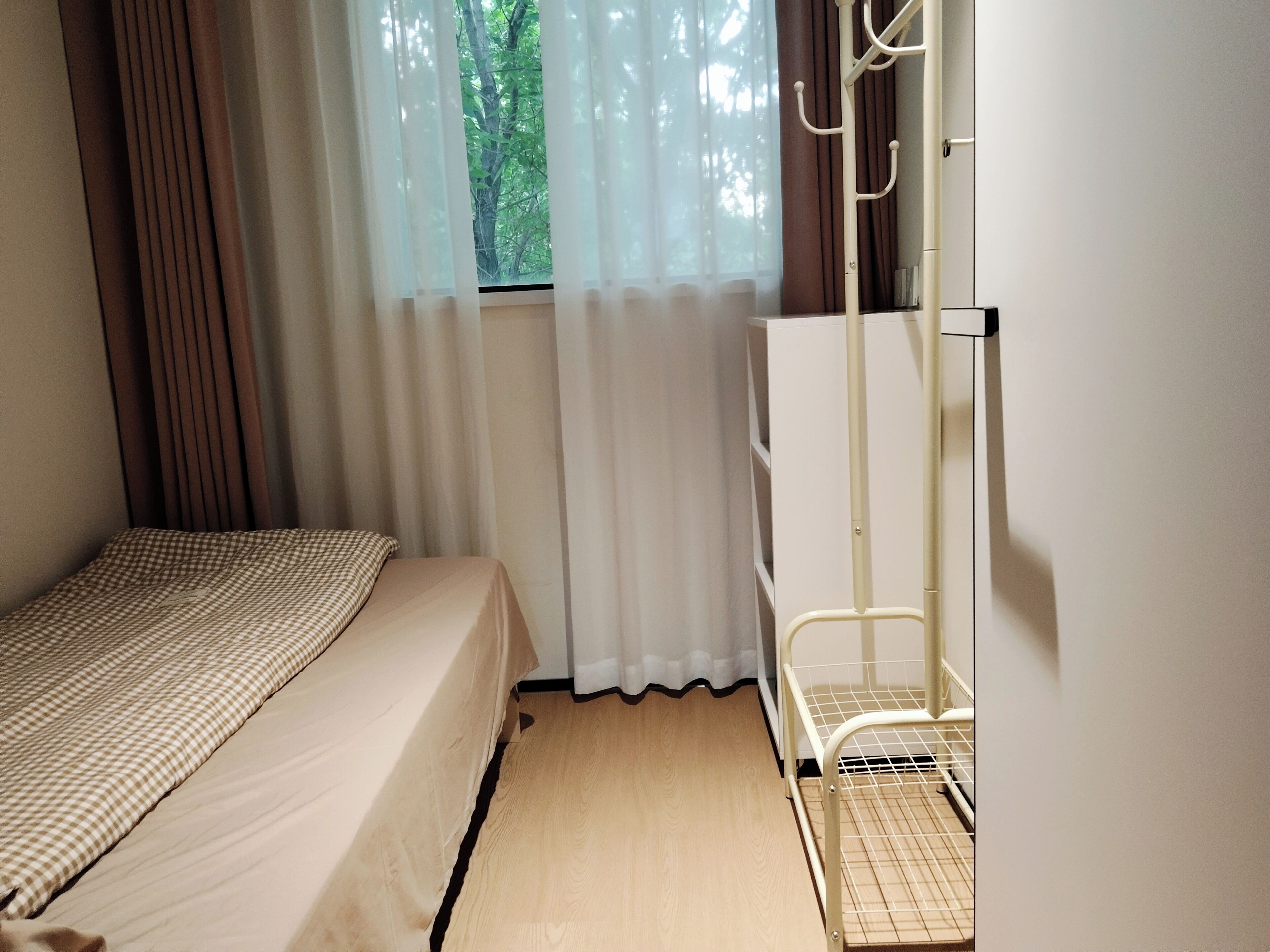 A bedroom with a bed, a wardrobe, a window with curtains, and a radiator.