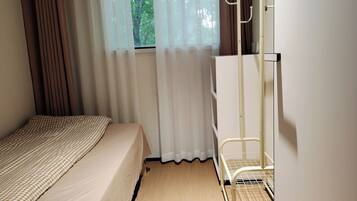 A bedroom with a bed, a wardrobe, a window with curtains, and a radiator.