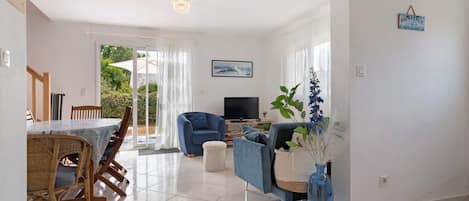 A spacious living room with a dining area, a TV, and a blue sofa.