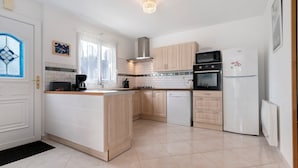 A modern kitchen with a central island, built-in oven, microwave, and refrigerator.