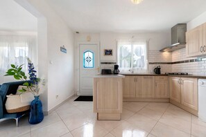 Una cucina moderna con isola centrale, pensili in legno chiaro e zoccolo schienale in piastrelle bianche.