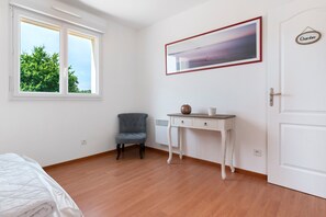 Una stanza con un letto, una scrivania con una sedia, una finestra con vista sugli alberi e una porta con un cartello.