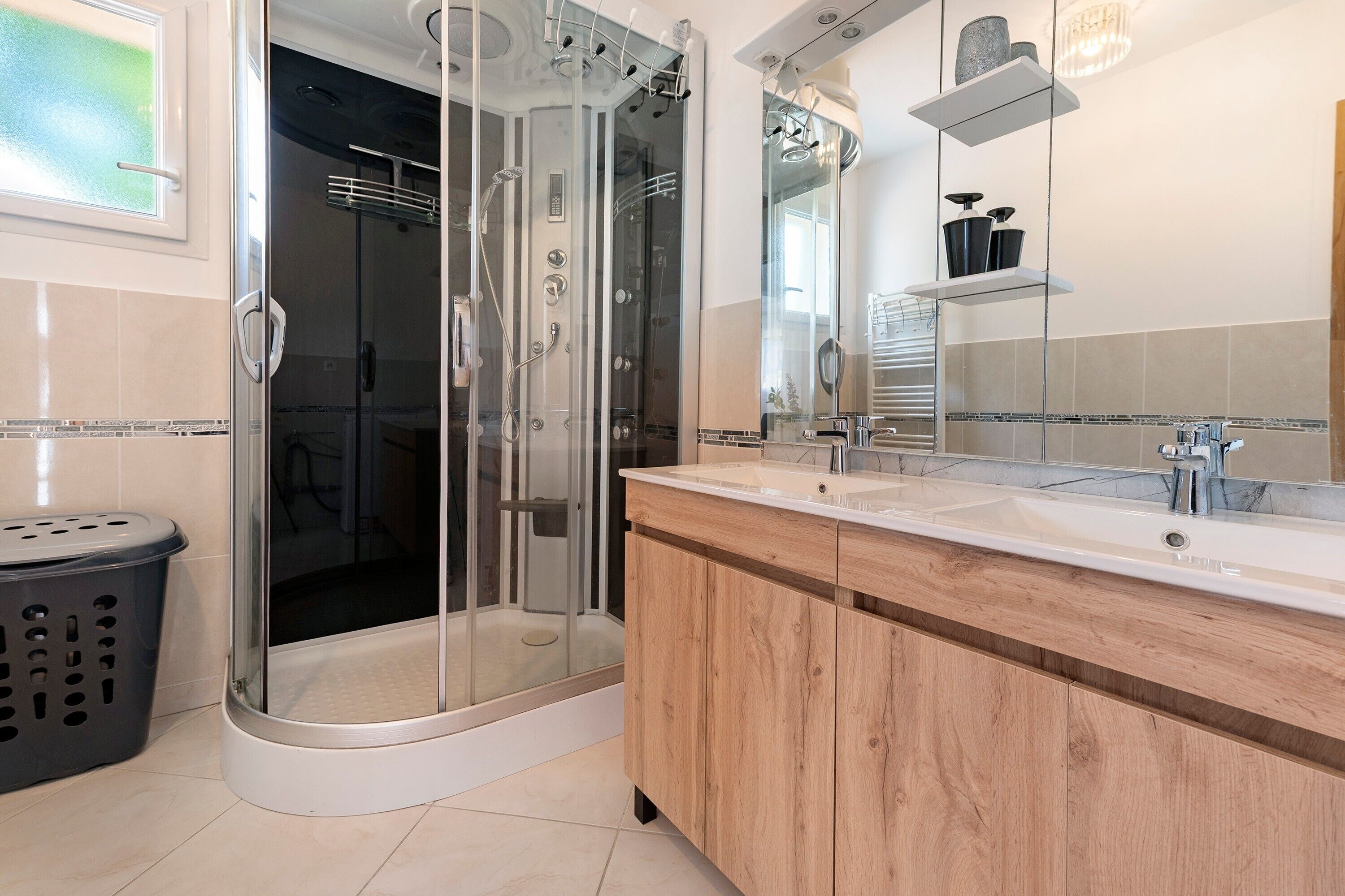 Un baño moderno con ducha de vidrio, tocador de madera y un espejo grande.